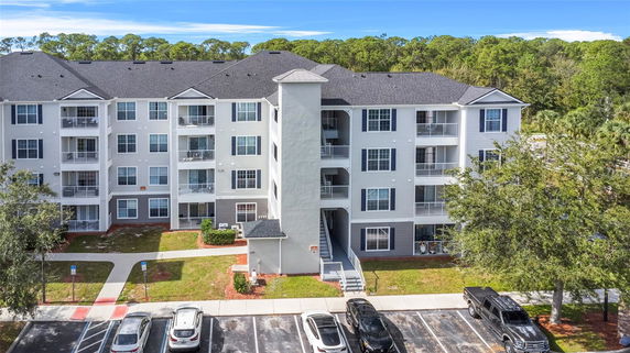 Front view of a multi-story apartment building with parking area.