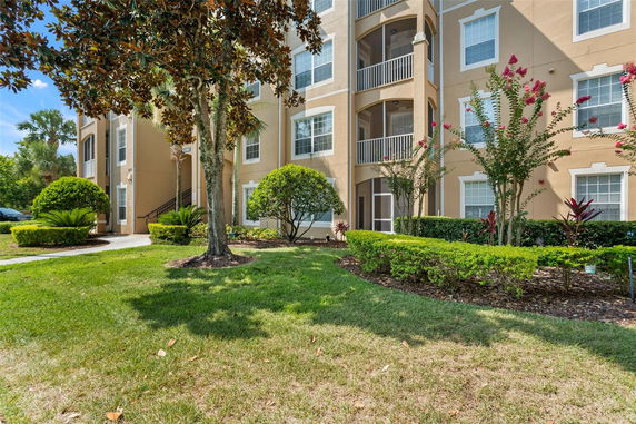 Front view of a multi-story residential building with balconies and landscaped garden.