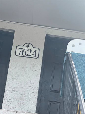Front view of a building entrance with a numbered sign and stairs.