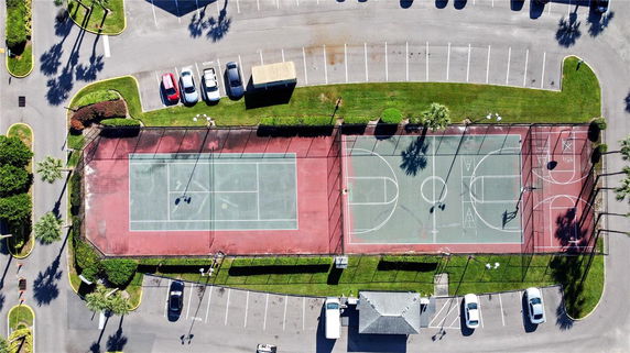 Aerial view of tennis and basketball courts surrounded by a parking area.