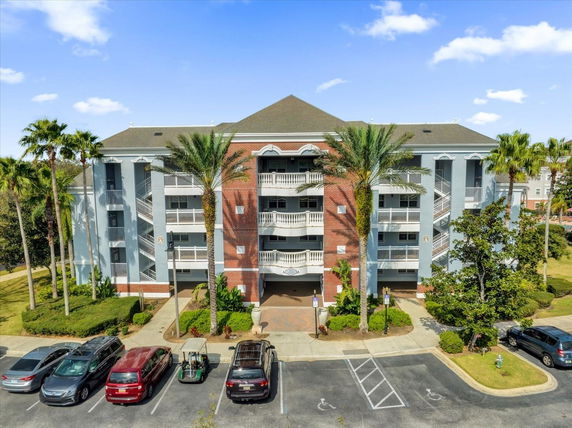 Front view of a multi-story residential building with balconies and parking area.