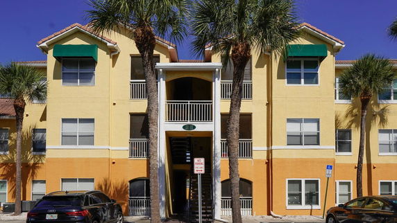 Front view of a multi-story residential building with two staircases and palm trees.