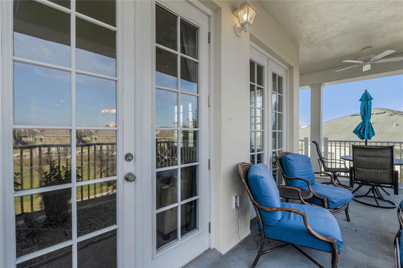 Outdoor patio area with blue cushioned chairs and a table set, overlooking surrounding buildings.