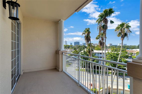 Balcony view overlooking cityscape with tall buildings and palm trees.