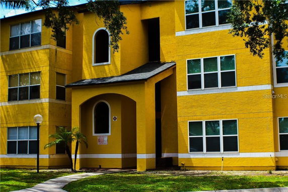 Front view of a multi-story yellow building with arched entryway.