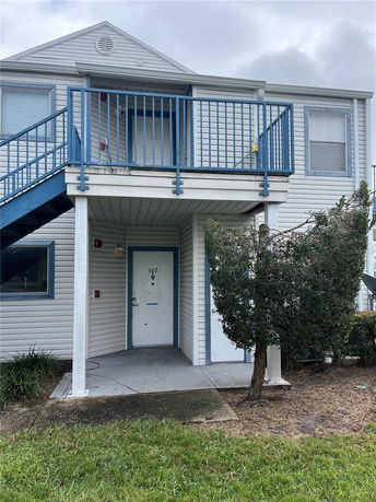 Front view of a two-story apartment building with exterior stairs and blue railings.