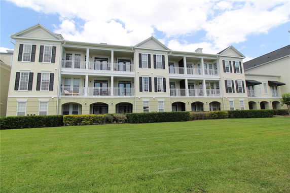 Front view of a multi-story building with balconies and shutters.