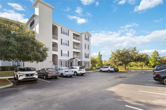 Parking area in front of a multi-story building with balconies.