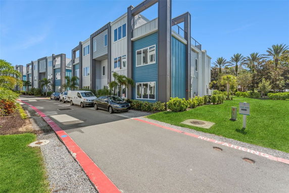 Front view of a modern multi-story residential building with blue and white panels.