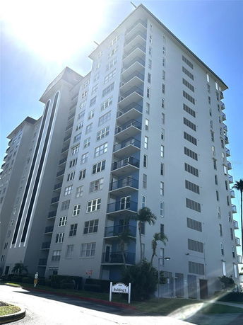 Front view of a tall residential building with multiple balconies.