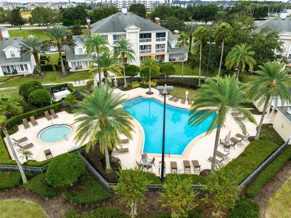 Aerial view of a swimming pool area surrounded by trees and residential buildings.