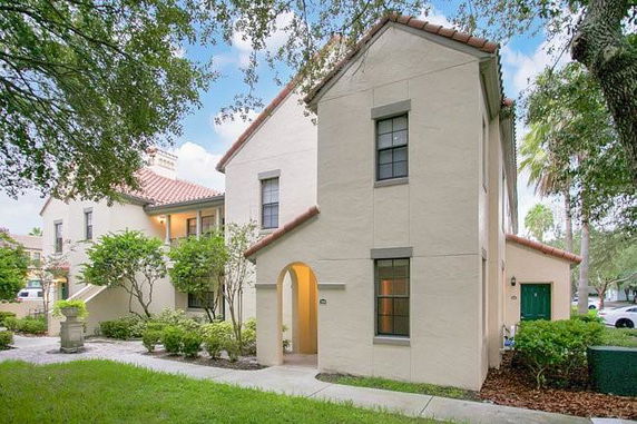 Front view of a two-story house with a tile roof and arched doorway.