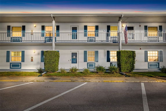 Front view of a two-story building with a balcony and flagpole.