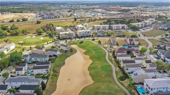 Aerial view of a residential area with houses, a golf course, and surrounding landscape.