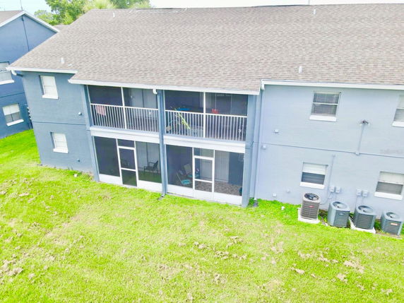 Rear view of a two-story building with balconies and ground floor patios.