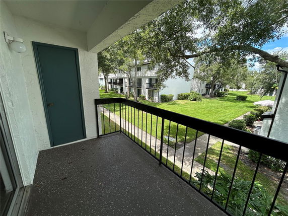 View from a balcony looking out at grass and neighboring buildings.