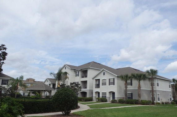 Front view of a multi-story residential building with a grey roof and white exterior.