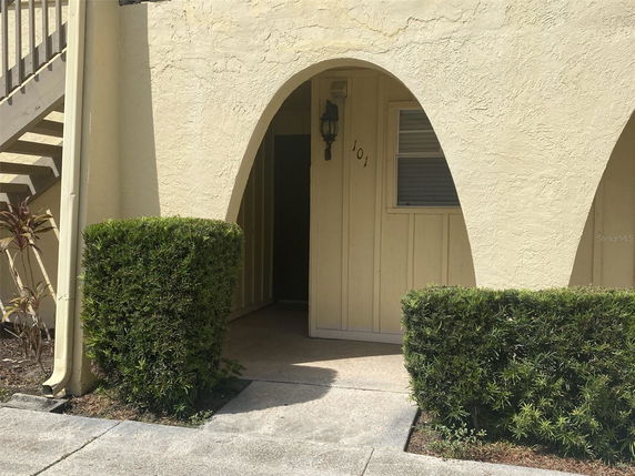 Front view of a building entrance with arched openings and stairway on the side.