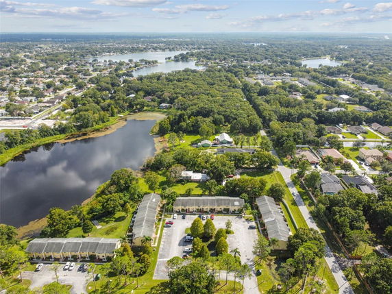 Aerial view of a residential area with several buildings, roads, and a lake surrounded by trees.