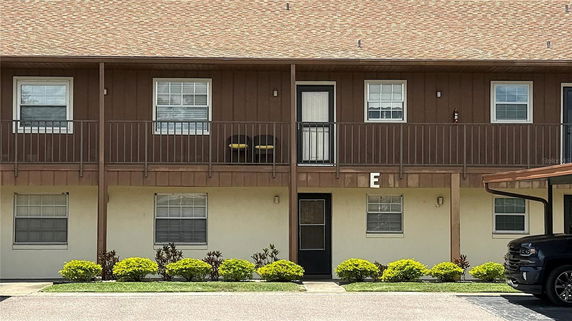 Front view of a two-story building with balconies and covered parking.