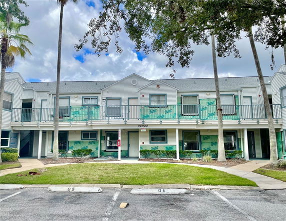 Front view of a two-story building with balconies and parking spaces.