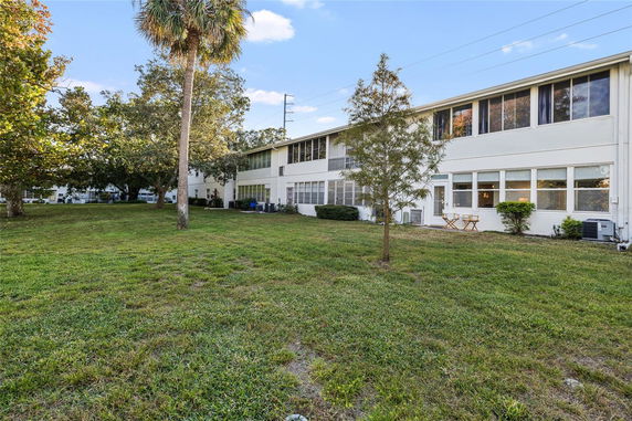 Rear view of a two-story building with large windows and a grassy yard.