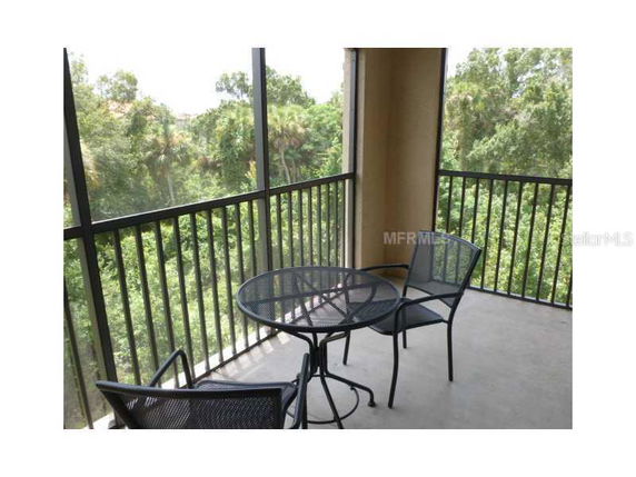 Balcony with metal table and chairs overlooking a view of trees.