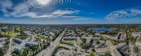 Panoramic view of a town with numerous buildings, roads, and a large body of water in the distance.