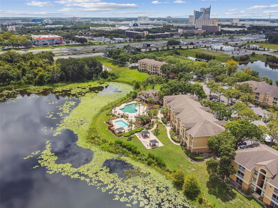 Aerial panoramic view of a residential complex with a swimming pool and nearby lake.