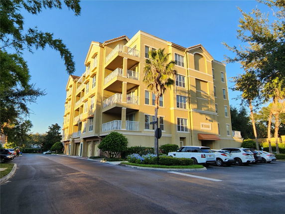 Front view of a multi-story apartment building with balconies and parking area.