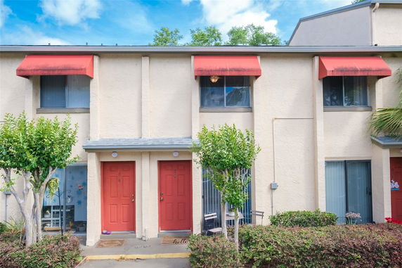 Front view of a two-story building with red doors and window awnings.