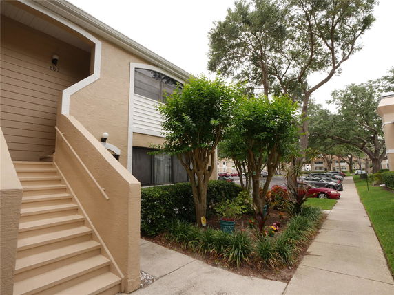 Front view of a multi-story residential building entrance with outdoor stairs.