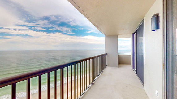 Balcony view overlooking the ocean and sky from a high-rise building.