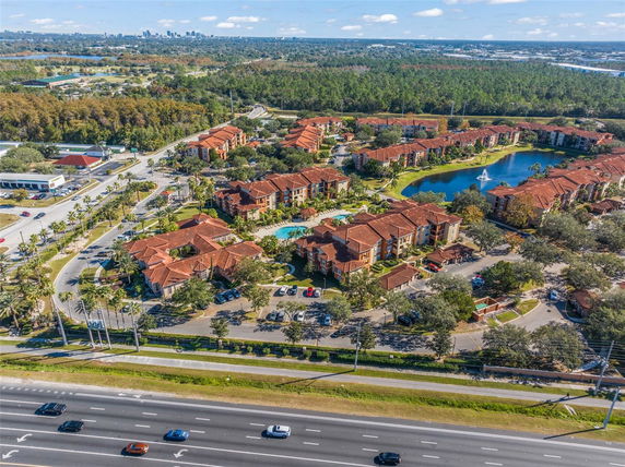Aerial view of a residential area with multiple buildings, swimming pool, and surrounding greenery.