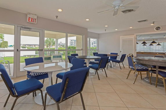 Indoor recreational area with tables and chairs, featuring large windows.