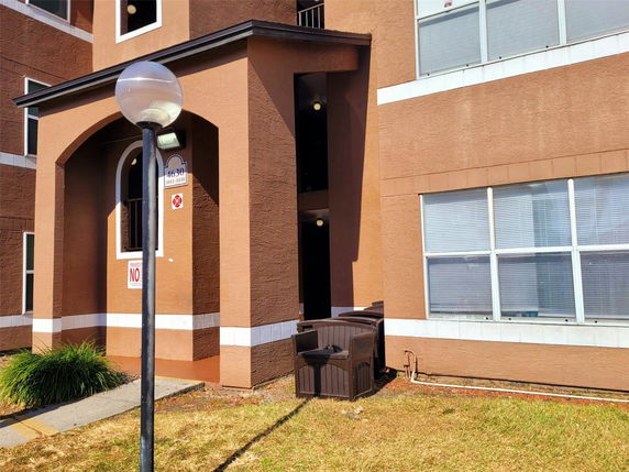 Front view of a brown building with large windows and an arched entryway.