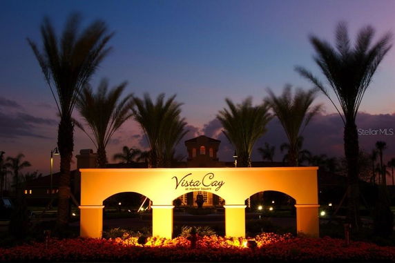 Front view of a building with illuminated sign and palm trees at dusk.