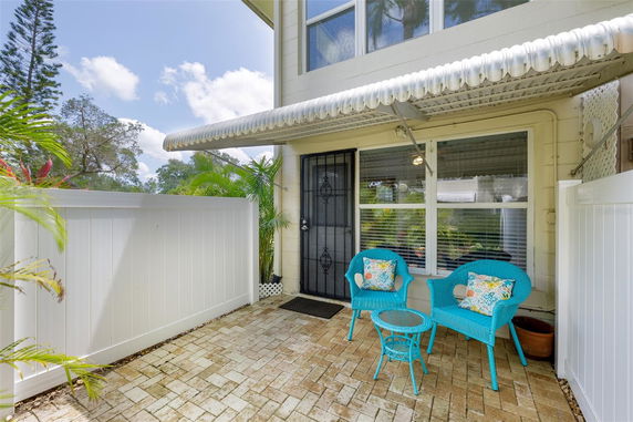 Front view of a house with a small patio area featuring blue chairs and a table.