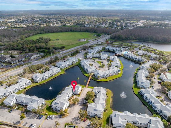 Aerial view of a residential complex with multiple identical buildings located around a central water body, depicting a wide expanse of the surrounding area.