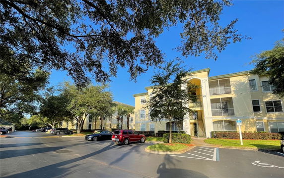 Front view of a multi-story residential building with balconies and a parking area.