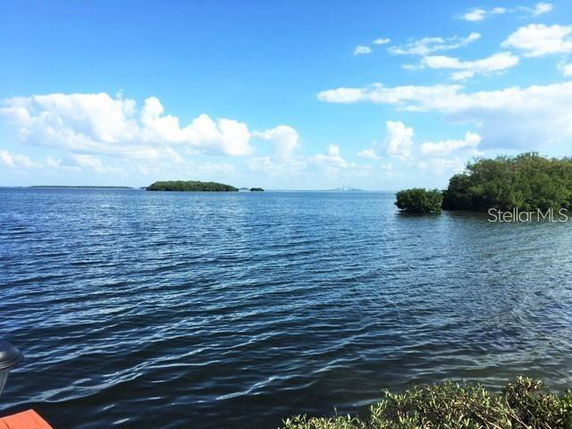 Panoramic view of a large body of water with small islands and a bridge in the distance under a blue sky with clouds.