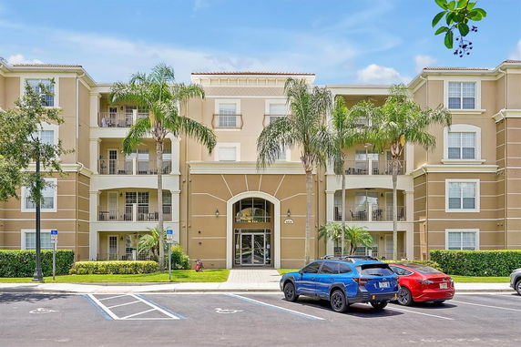 Front view of a multi-story residential building with balconies and palm trees.
