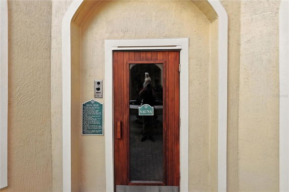 Entrance of a sauna with a wooden door and a sign indicating sauna rules.