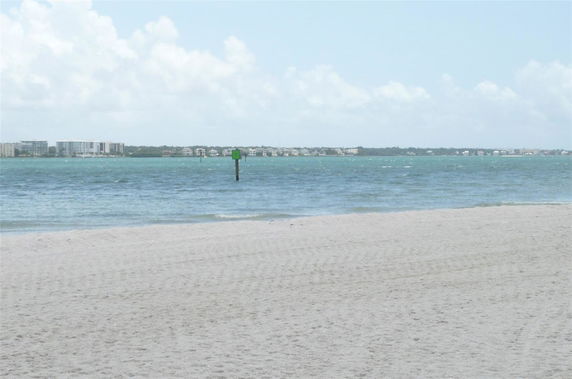 Wide angle view of beach and sea with distant buildings on the horizon.