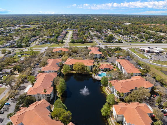 Panoramic aerial view of a residential complex with multiple buildings and water feature.