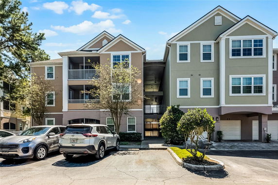 Front view of a multi-story residential building with balconies and a parking area.