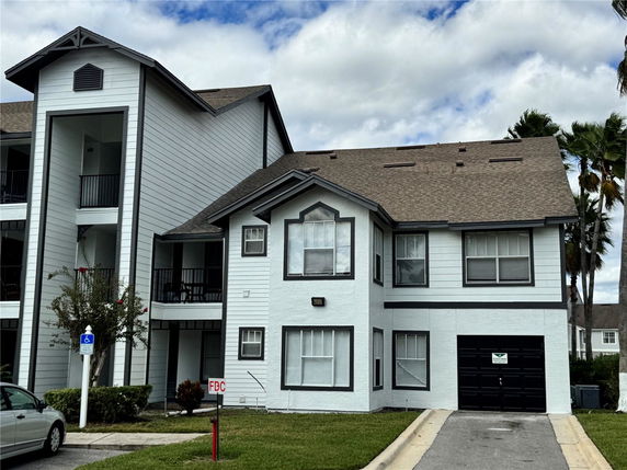 Front view of a two-story house with an attached garage and overhanging roof design.