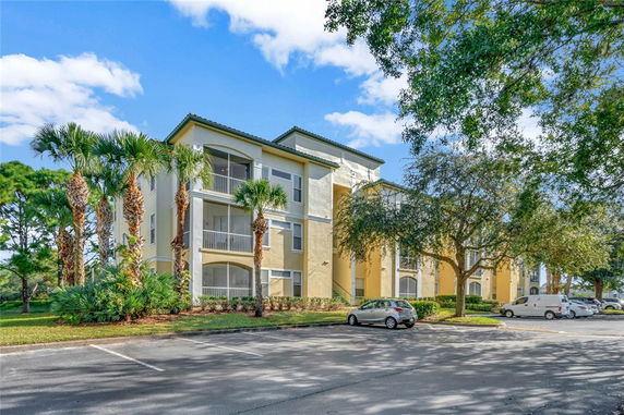 Front view of a multi-story apartment building with balconies and palm trees.