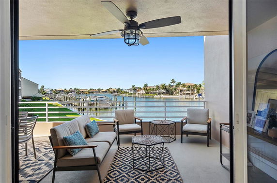 Outdoor seating area on a balcony with a view of the water and surrounding houses.