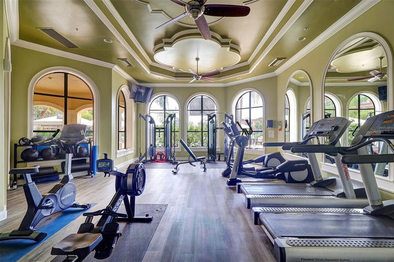 Interior view of a fitness room with exercise equipment, treadmills, and large windows.